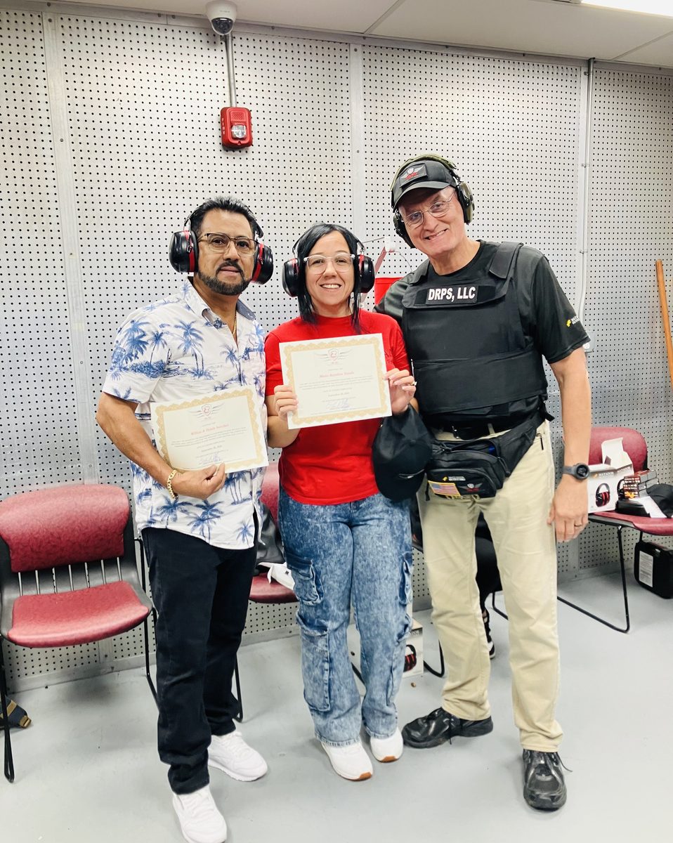 Two CCW class graduates with their certificates and instructor